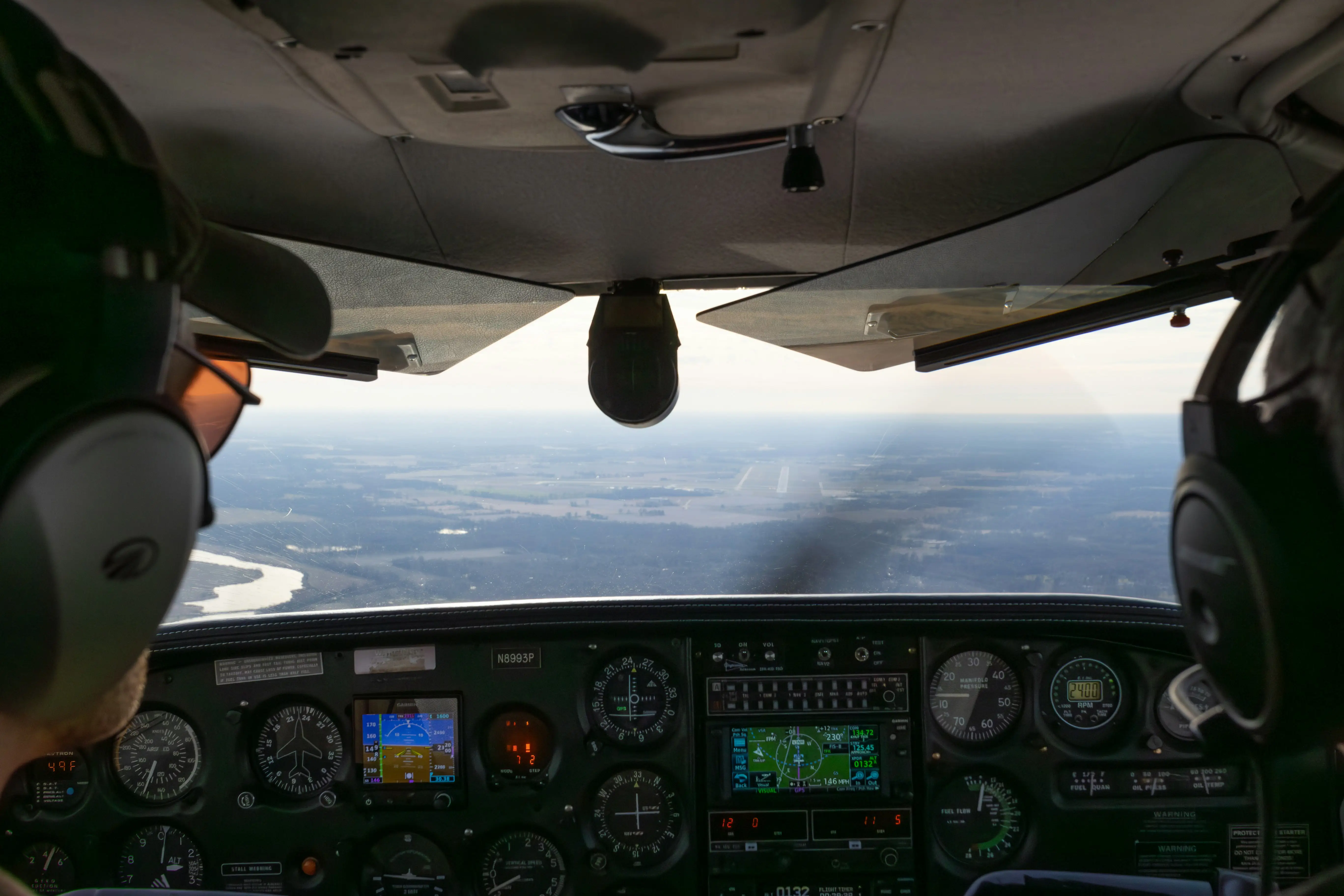 A small aircraft flying over a scenic landscape during sunset.